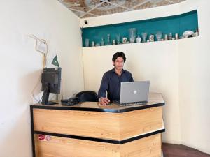 a man sitting at a desk with a laptop computer at Ameer lodge in Hunza Valley
