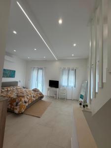 a white bedroom with a bed and a television at Al58 Casa Vacanze in Villasmundo
