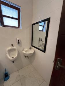 a bathroom with a urinal and a sink and a mirror at Recanto da Paz in Tarrafal +25 photos