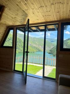 a room with a large window with a view of a lake at Camping Temali T&M in Arrëz +25 photos