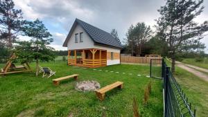 a small cabin with benches in a yard at Dom nad jeziorem Serwy in Serwy
