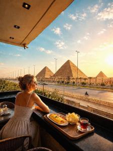 a woman sitting at a table looking out at pyramids at New White Pyramids Inn in Cairo