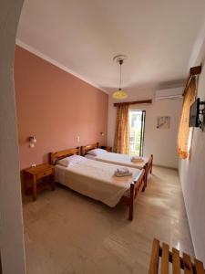 a bedroom with two beds and a window at Hotel Omirico in Gouvia