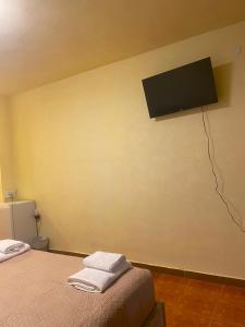 a room with a bed and a television on the wall at Dina's Rooms Himara in Himare