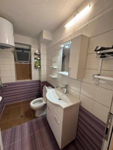 a bathroom with a white toilet and a sink at Dina's Rooms Himara in Himare