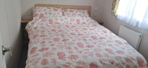 a bed with a pink and white bedspread with flowers on it at Kazamar in East Mersea +24 photos