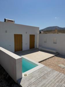 a white building with a swimming pool in front of it at Gaia Elysian Sea View New Golden Beach Piso Livadi in Kampos Paros