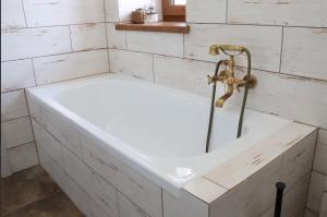 a white bath tub in a white tiled bathroom at Dům U babičky in Laškov +29 photos
