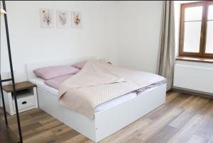 a white bed in a room with a window at Dům U babičky in Laškov