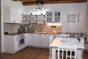 a kitchen with white cabinets and a table at Dům U babičky in Laškov