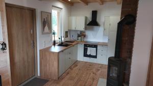 a kitchen with white cabinets and a stove top oven at Dom nad jeziorem Serwy in Serwy