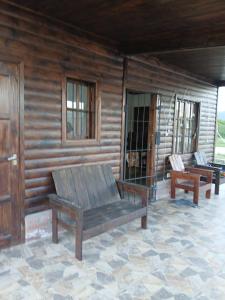 a porch of a log cabin with two benches at Cabañas amanecer alegre in Salta