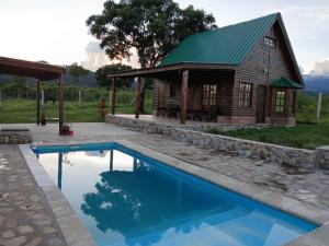 a log cabin with a swimming pool and a building at Cabañas amanecer alegre in Salta +8 photos