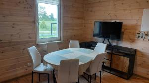 a dining room with a table and chairs and a television at Dom nad jeziorem Serwy in Serwy