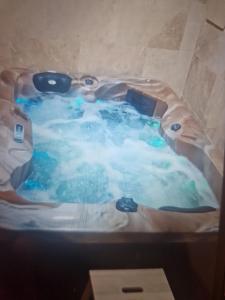 a bath tub with blue water in it at Petit appartement avec jacuzzi in Bédarrides