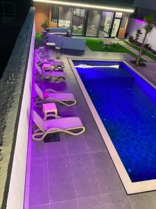 a row of pink lounge chairs next to a swimming pool at Aurora villa in Rrushkull