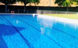 a large blue swimming pool with a tennis court at CASA RURAL EL TRASTERO DE CARMELO in Maello