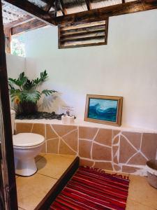 a bathroom with a toilet and a painting on the wall at Fare Hau Lodge in Tahaa +14 photos