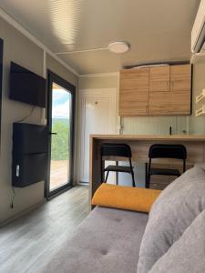 a room with a bed and a kitchen with two chairs at Piva Chill in Plužine