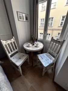 two chairs and a table in a room with a window at Prowansalski Sen - pokój z łazienką nr 3 in Poznań