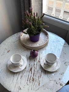 a table with two cups and plates and a potted plant at Prowansalski Sen - pokój z łazienką nr 3 in Poznań