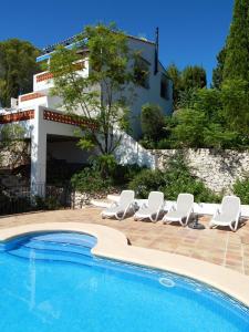 a pool with chairs and a house in the background at Casita Viveca in Orba