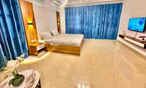 a bedroom with a bed with blue curtains and a television at Résidence La Rose des Vents in Cotonou