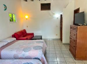 a bedroom with a bed and a couch and a tv at Bungalows El Mirador in Cruz de Huanacaxtle