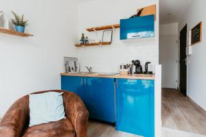 a kitchen with blue cabinets and a leather chair at Appartement - Michelet in Le Havre +17 photos