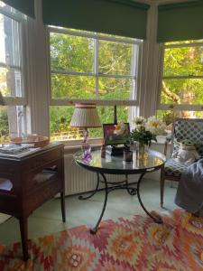 a living room with a table and a desk and windows at 30 Park Street in Hungerford