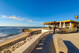 a building on a beach next to the ocean at Gaivota Erudita in Buarcos