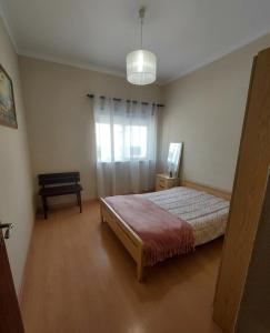 a bedroom with a bed and a table and a window at Gaivota Erudita in Buarcos