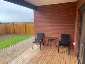 two chairs and a table on a deck with a brick wall at Darley Retreat in Darley