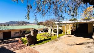 a house with a tree in the driveway at Jwalaboholo Mountain View Guest House in Ficksburg