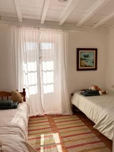 a bedroom with two beds and a window with white curtains at Casa Mirabel Laurel in Fene