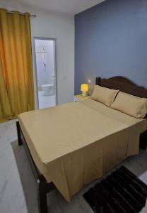 a large bed in a bedroom with a yellow curtain at Kaza Branka in Sal Rei