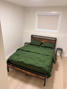 a bedroom with a bed with green sheets and a window at Cozy home in Burnaby