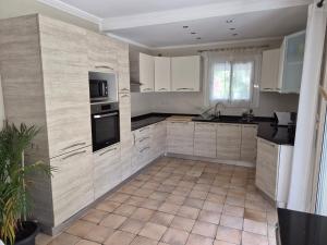 a kitchen with white cabinets and a tile floor at Rez de villa avec piscine in Menton