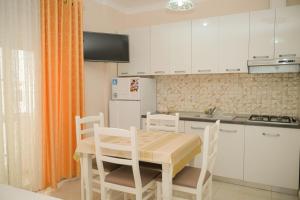 a kitchen with white cabinets and a table and chairs at Vila Vitoria in Shëngjin