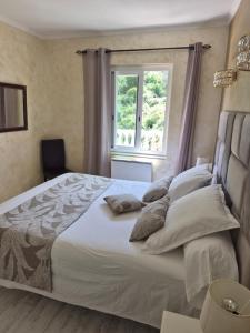a bedroom with a large white bed with a window at Rez de villa avec piscine in Menton +22 photos