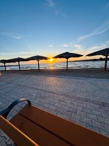 a bench on a beach with a sunset in the background at Holiday House Zaton in Zaton