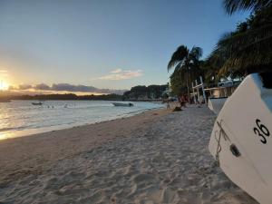 a surfboard sitting on a beach with people in the water at Nid du Lagon in Sainte-Anne
