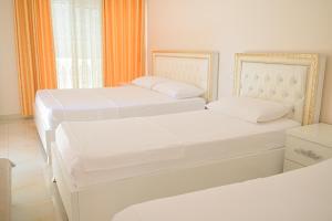 two white beds in a room with a window at Vila Vitoria in Shëngjin