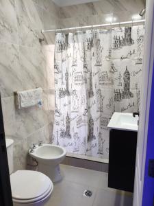 a bathroom with a shower curtain with a toilet and a sink at Complejo las Catalinas Dto 2 A in Puerto Madryn +13 photos