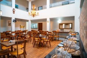 a restaurant with wooden tables and chairs and a chandelier at Hotel Portal do Descobrimento in Porto Seguro