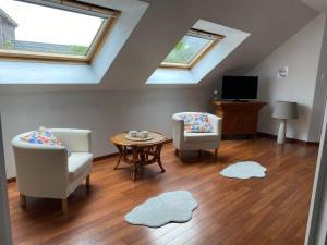 a living room with two chairs and a table and two windows at La cour des hôtes in Fenain