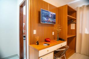 a room with a desk with a television on a wall at Hotel Portal do Descobrimento in Porto Seguro