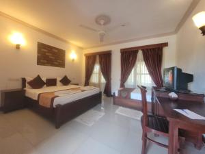 a bedroom with a bed and a desk with a computer at Vintara Wild Hambanthota in Hambantota