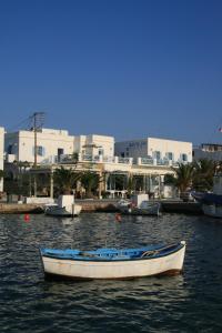 a white boat in the water with buildings in the background at Hotel Mantalena in Antiparos Town