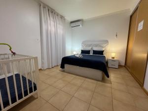 a bedroom with a bed and a crib in it at Alforra Residence 1-T2-centro-praias-Levadas in Câmara de Lobos